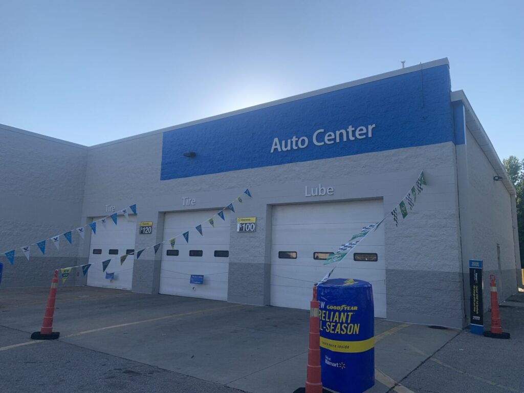 Exterior of an auto center with three service bay doors labeled Tire and Lube, and a Goodyear tire display in front.