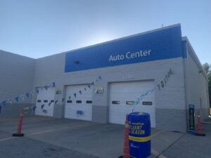 Exterior of an auto center with three service bay doors labeled Tire and Lube, and a Goodyear tire display in front.