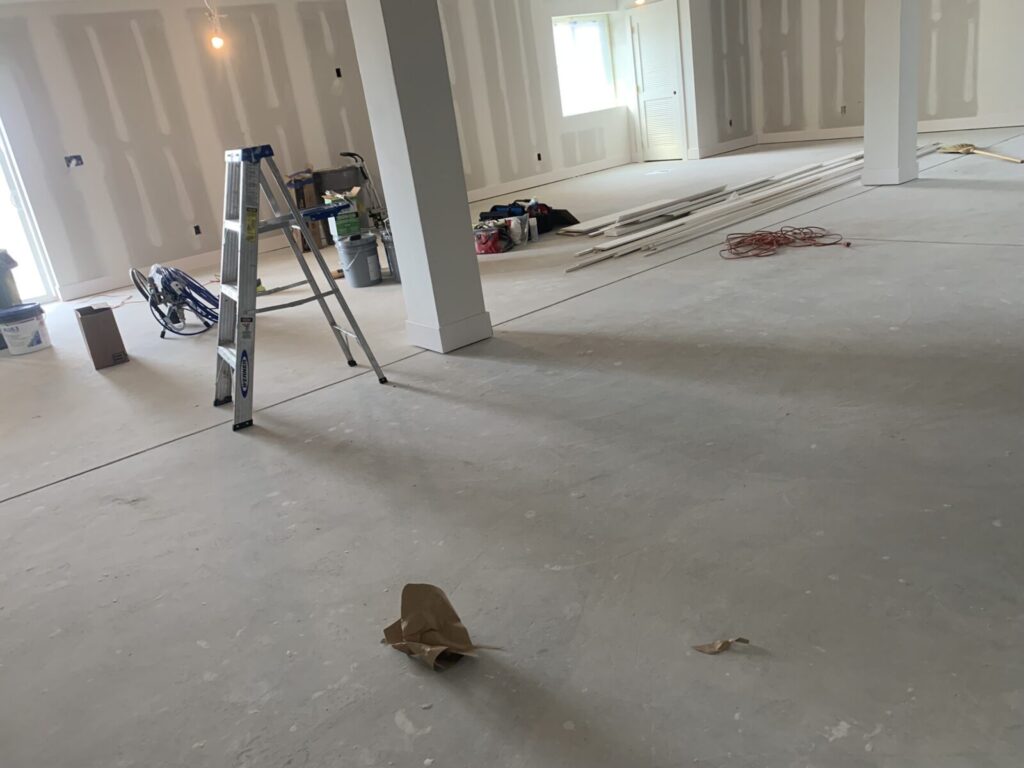 Unfinished room with drywall, a ladder, construction tools, and materials scattered across the floor.