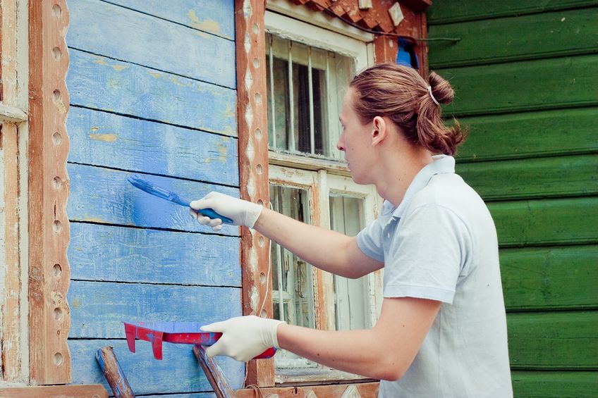 male painter paints blue wooden wall
