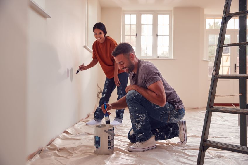 couple painting test squares on wall as they decorate room in new home together